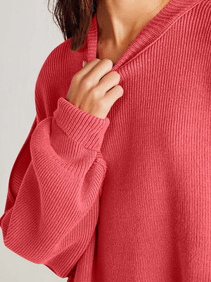 Close-up of a cozy side-slit sweater in coral with a round neck, showcasing soft ribbed texture, perfect for winter warmth.