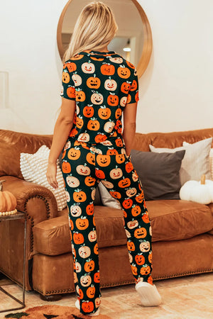 Back view of a woman wearing a pumpkin printed short sleeve top and pants lounge set, sitting on a cozy couch.