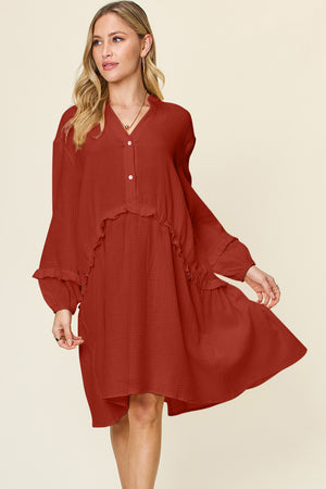 Model wearing a rust red double take full-size texture half button ruffle trim dress with flowy sleeves.
