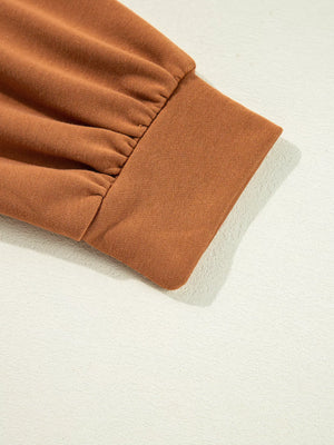 Close-up of the cuff detail on a brown notched long sleeve top, showcasing its soft fabric and gathered design.
