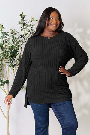Plus-size model wearing Basic Bae black ribbed round neck long sleeve top with side slit, styled with blue jeans.