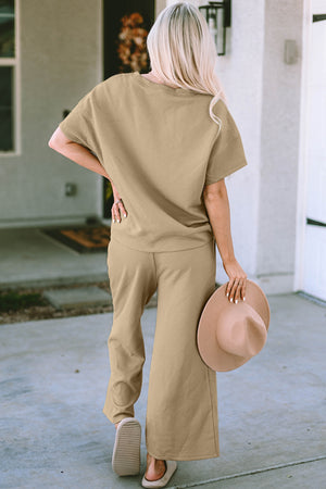 Woman wearing a beige double take texture top and pants set, holding a hat, stylish casual outfit.