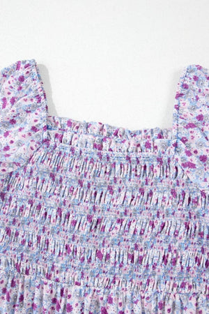 Close-up of the smocked bodice of a tiered floral dress, featuring delicate purple and blue flower patterns.