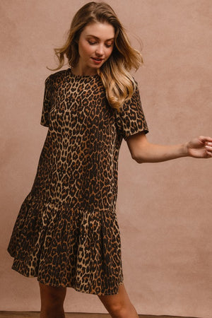 Woman modeling a leopard print tie back round neck short sleeve dress with ruffled hem.