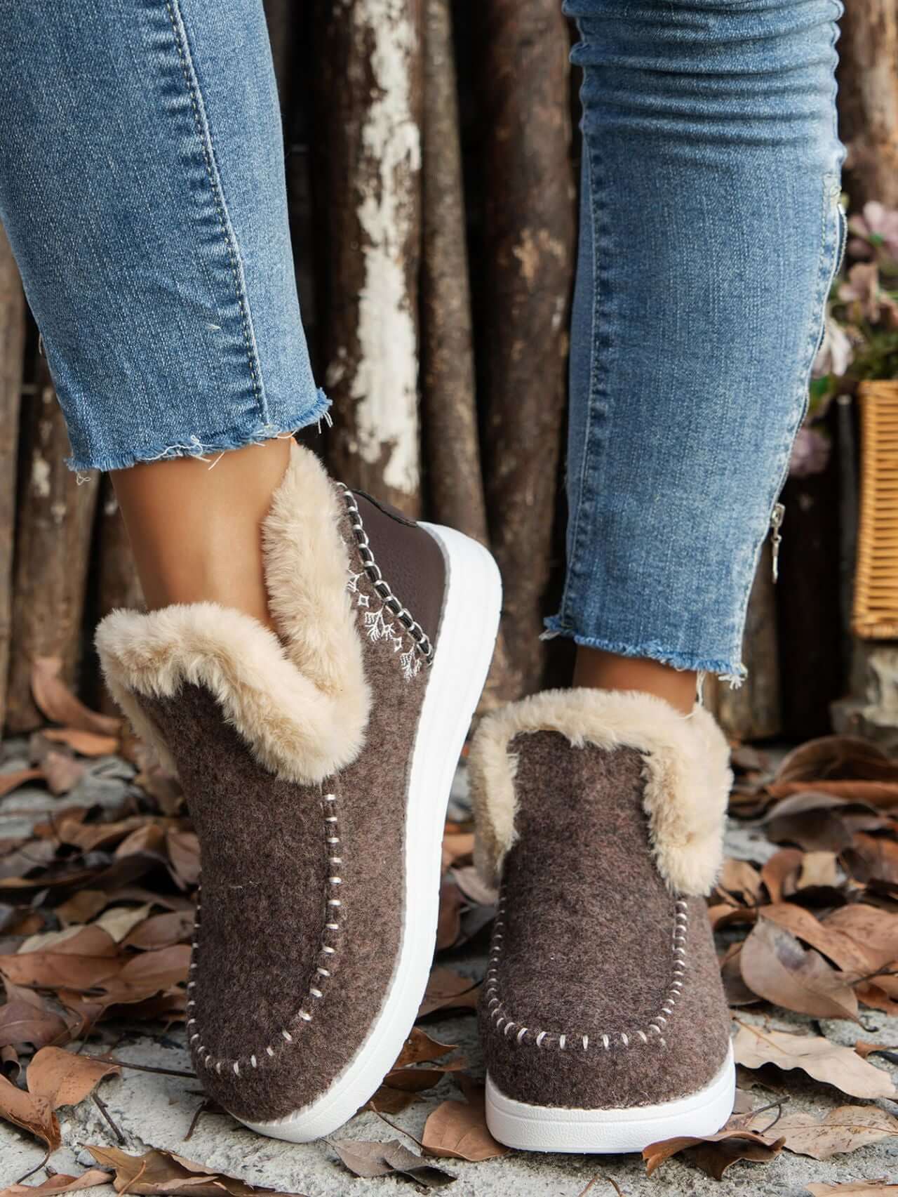 Furry suede round toe flat sneakers with faux fur detailing, worn with distressed denim jeans amidst autumn leaves.