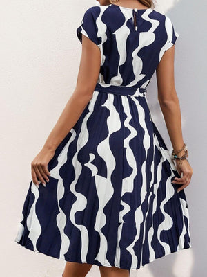 Navy and white tied pleated printed cap sleeve dress showcasing a wavy design, perfect for casual outings.