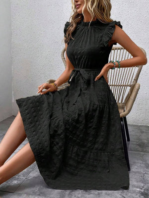 Tied ruffled cap sleeve midi dress in black, showcased on a model sitting in a stylish indoor setting.