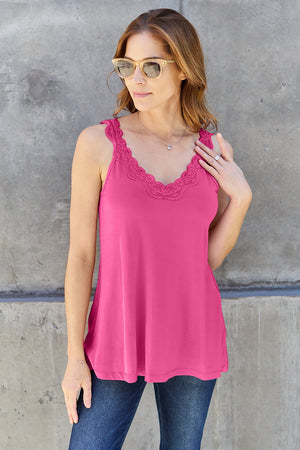 Model wearing a pink Basic Bae lace detail V-neck cami with sunglasses and jeans against a concrete wall.