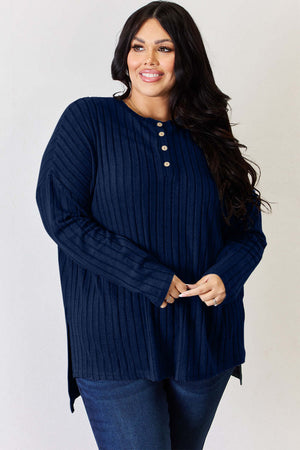 Curvy model wearing a navy ribbed half button long sleeve high-low t-shirt, showcasing a stylish slit design.
