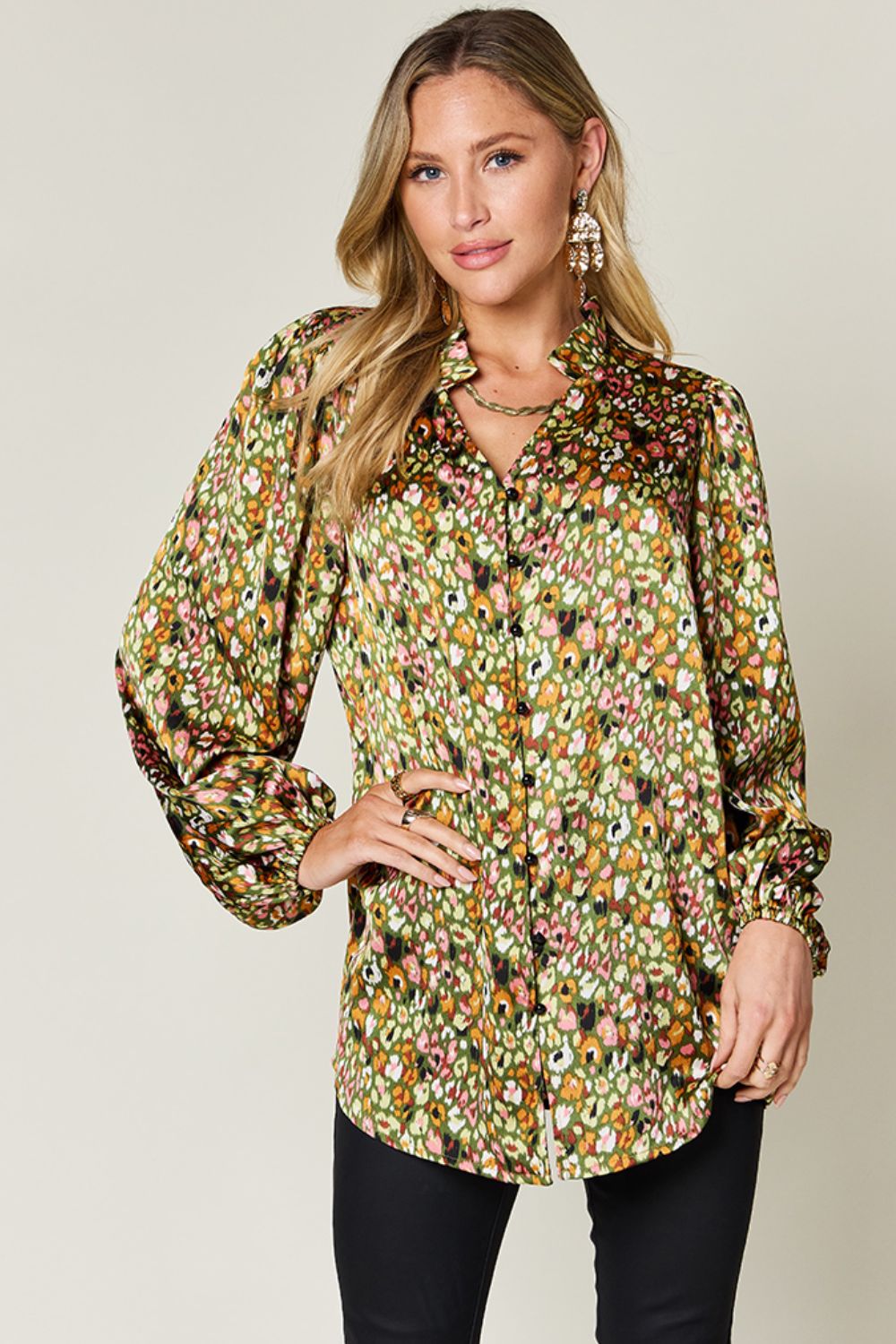 Model wearing a vibrant floral printed long sleeve blouse with frill detail, styled with black pants.