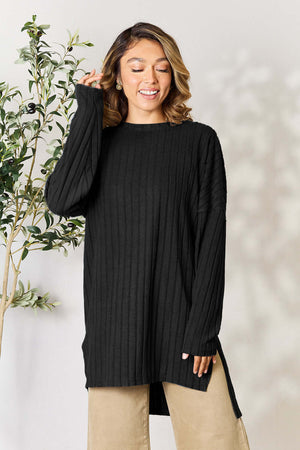 Model wearing a black ribbed long sleeve slit top, showcasing a relaxed fit and high-low design.