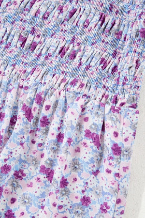 Close-up of tiered floral fabric with smocked detailing in shades of purple and blue, perfect for a stylish maxi dress.