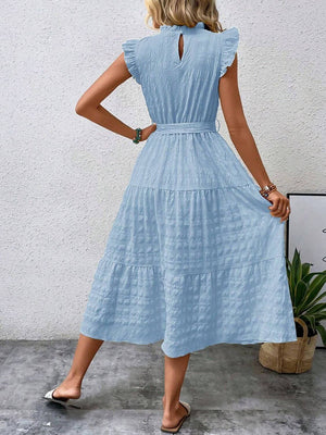 Back view of a tied ruffled cap sleeve midi dress in light blue, featuring a tiered design and keyhole detail.