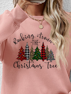 Woman wearing a pink sweatshirt with a Christmas tree graphic design, perfect for holiday festivities.
