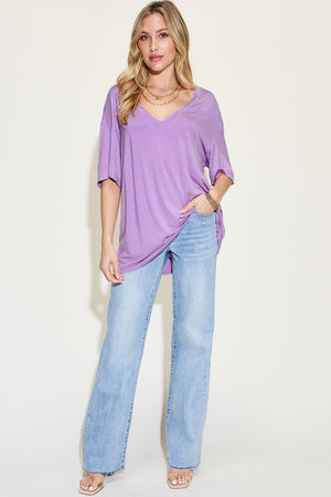 Model wearing Basic Bae Full Size Bamboo V-Neck Drop Shoulder T-Shirt in lavender with wide-leg jeans.