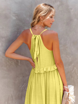 Model wearing a ruffled sleeveless tiered maxi dress with a tie back in vibrant yellow, showcasing a stylish summer look.