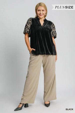 Umgee plus size black velvet blouse with embroidered sleeves, styled with beige pants for a chic look.