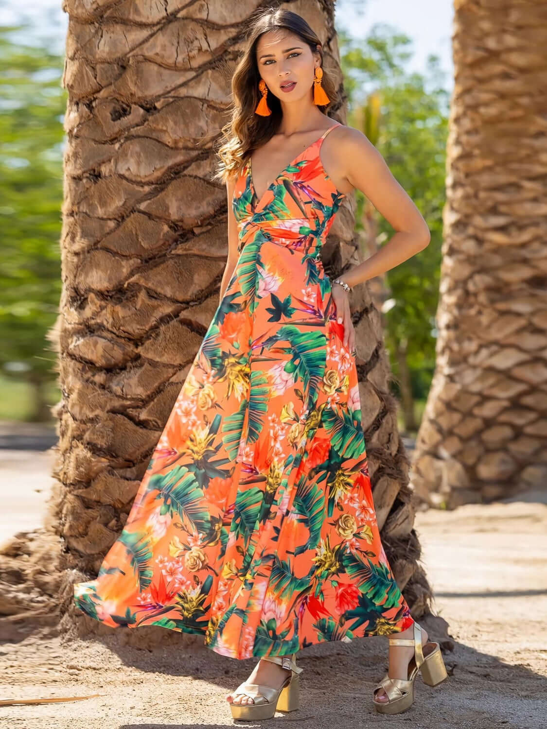Model wearing a Twisted Printed V-Neck Cami Dress with vibrant tropical print, standing by palm trees on a sunny day.