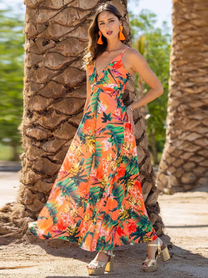 Model wearing a Twisted Printed V-Neck Cami Dress with vibrant tropical print, standing by palm trees on a sunny day.