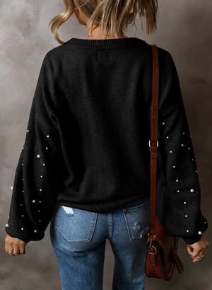 Back view of a black pearl detail long sleeve sweater styled with jeans and a shoulder bag.