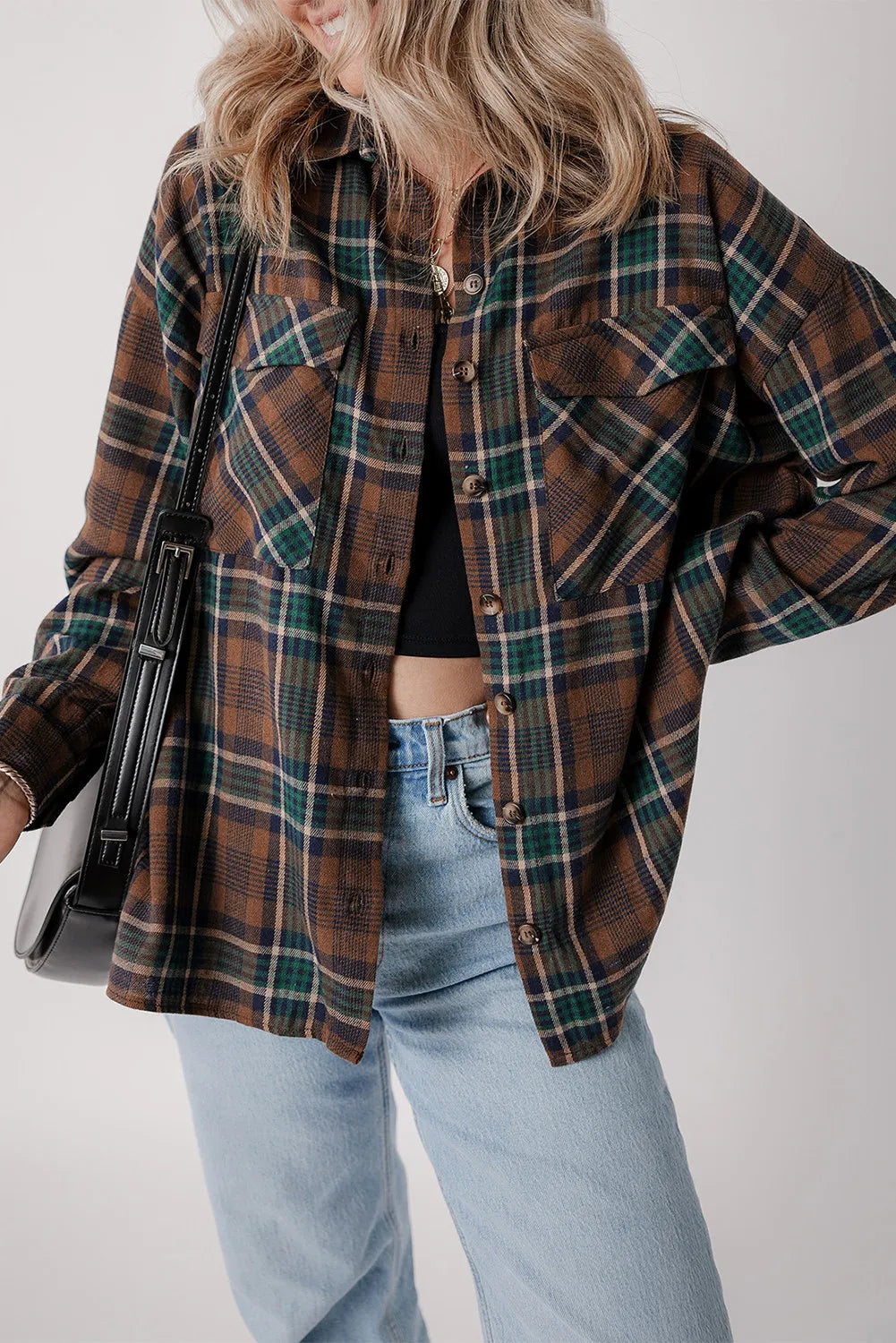 Stylish woman wearing a plaid button-up long sleeve jacket with pockets, paired with jeans and a cropped top.