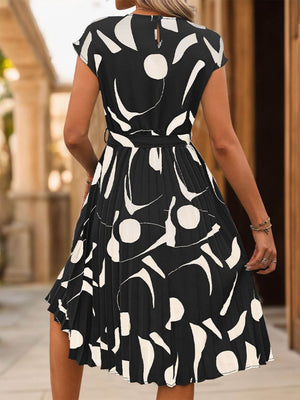 Back view of a tied pleated printed cap sleeve dress featuring a modern black and white pattern, perfect for casual outings.