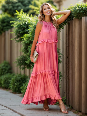 Ruffled sleeveless tiered maxi dress with pockets in pink, styled with sandals and a clutch, set against a garden backdrop.