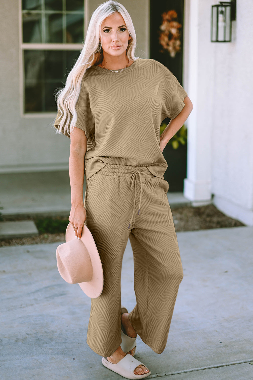 Stylish model wearing a beige double take short sleeve top and pants set with a drawstring and relaxed fit.