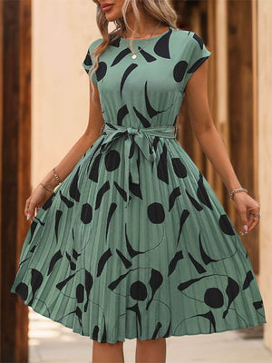 Tied pleated cap sleeve dress in green with black print, featuring a feminine silhouette and stylish design.