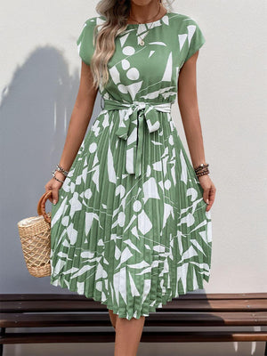 Tied pleated printed cap sleeve dress in green with white patterns, perfect for summer outings.