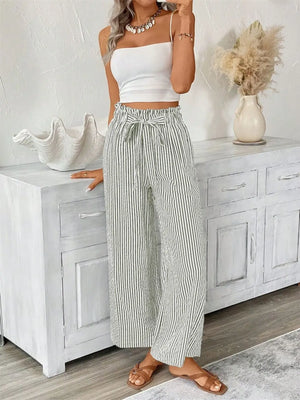 Stylish woman in white crop top and striped wide leg paper bag pants, showcasing a trendy summer outfit.