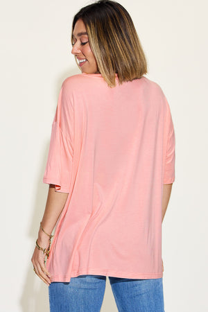 Back view of a woman in a pink v-neck drop shoulder t-shirt, showcasing its relaxed fit and soft fabric.