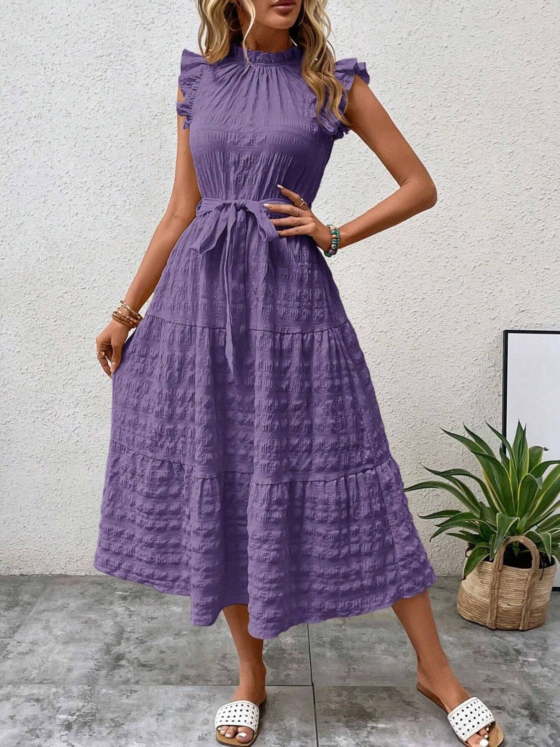 Tied ruffled cap sleeve midi dress in purple, featuring a tiered design and elegant silhouette, styled with casual footwear.