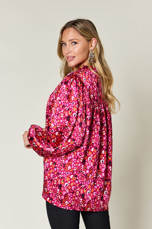 Model wearing a vibrant pink floral long sleeve blouse, featuring a trendy back design and stylish puff sleeves.