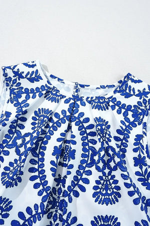 Close-up of a printed crew neck sleeveless top featuring blue floral patterns on a white background.