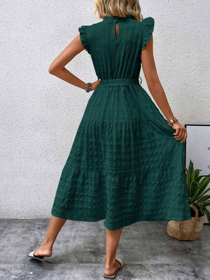 Back view of a woman wearing a tied ruffled cap sleeve midi dress in green, showcasing its flowing silhouette and elegant design.