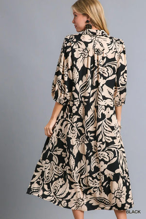 Back view of a woman wearing a black floral print tiered midi dress, showcasing its flowy silhouette and elegant design.
