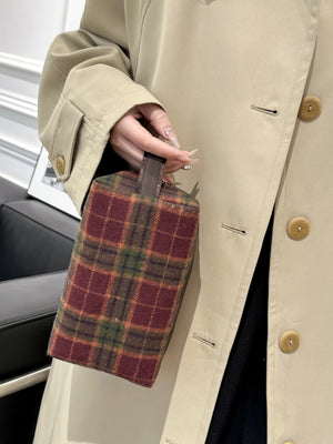 Stylish contrast plaid clutch with zipper being held, showcasing its unique design and small, compact size.