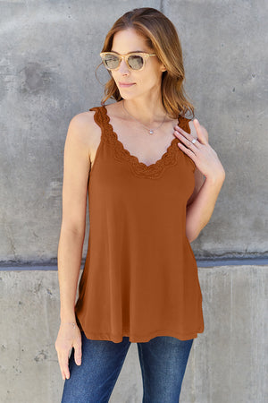 Woman wearing a basic brown lace detail v-neck cami, styled with jeans and sunglasses, against a concrete wall.