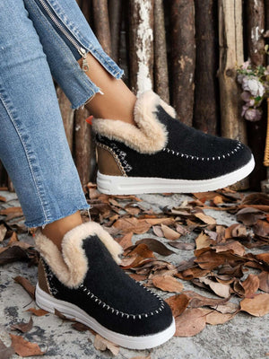 Furry suede round toe flat sneakers with fur soles, styled with denim on a leaf-covered ground.