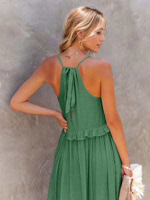 Back view of a woman in a green ruffled sleeveless tiered maxi dress with a tied detail and a flowy skirt.
