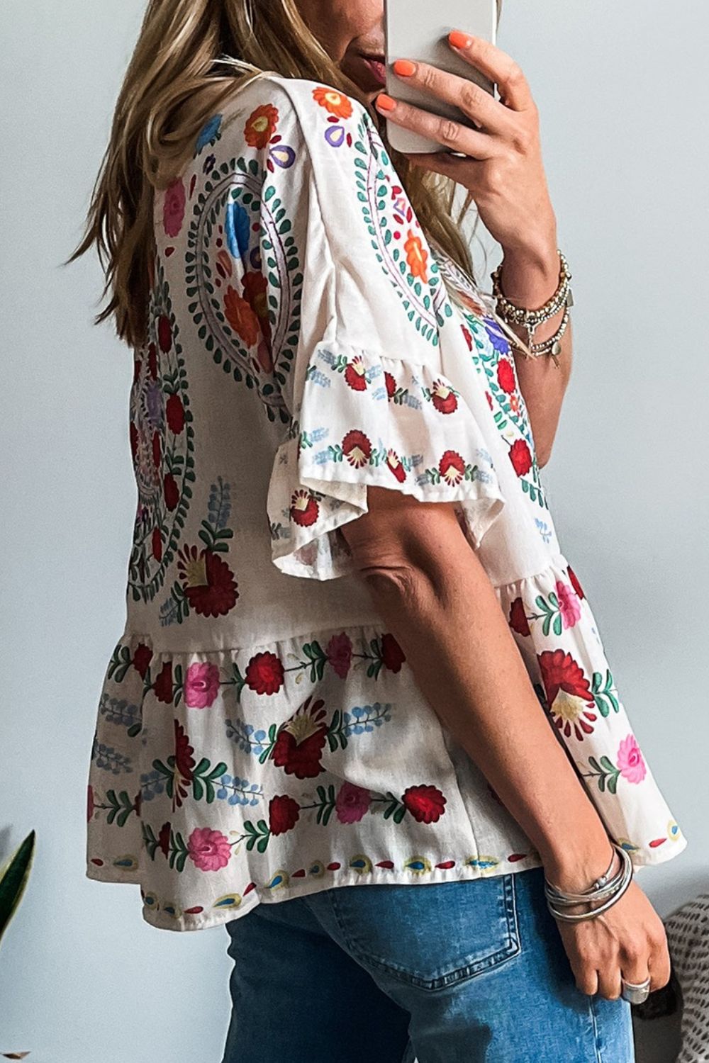 Floral print round neck blouse with ruffle trim, showcasing vibrant colors and lightweight design, ideal for casual wear.