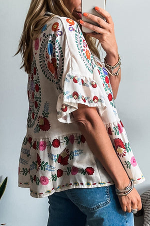 Floral print round neck blouse with ruffle trim, showcasing vibrant colors and lightweight design, ideal for casual wear.