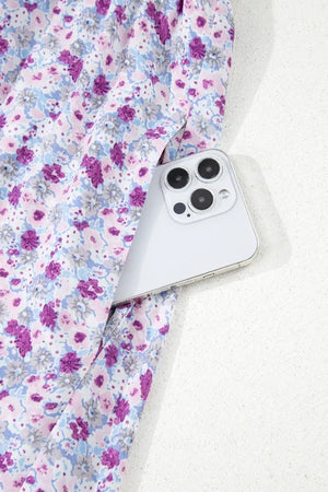 Close-up of a tiered floral maxi dress with a smartphone tucked into the fabric, showcasing its vibrant pattern.