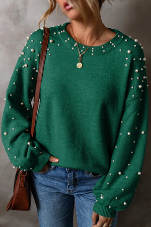 Emerald green round neck long sleeve sweater with pearl details, styled with blue jeans and layered necklaces.