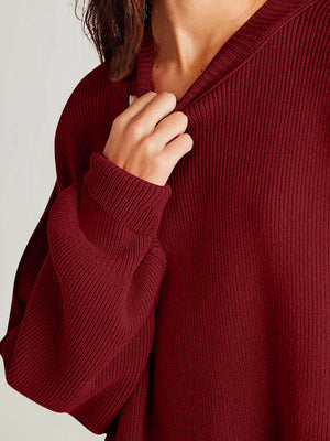 Close-up of a person wearing a burgundy side-slit sweater with a cozy round neck and ribbed texture.