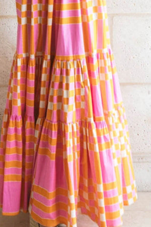 Color block tie shoulder dress in pink and yellow, featuring a tiered design and playful patterns.