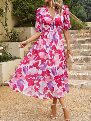 Model wearing a vibrant printed puff sleeve midi dress in pink and purple floral design, perfect for summer styles.