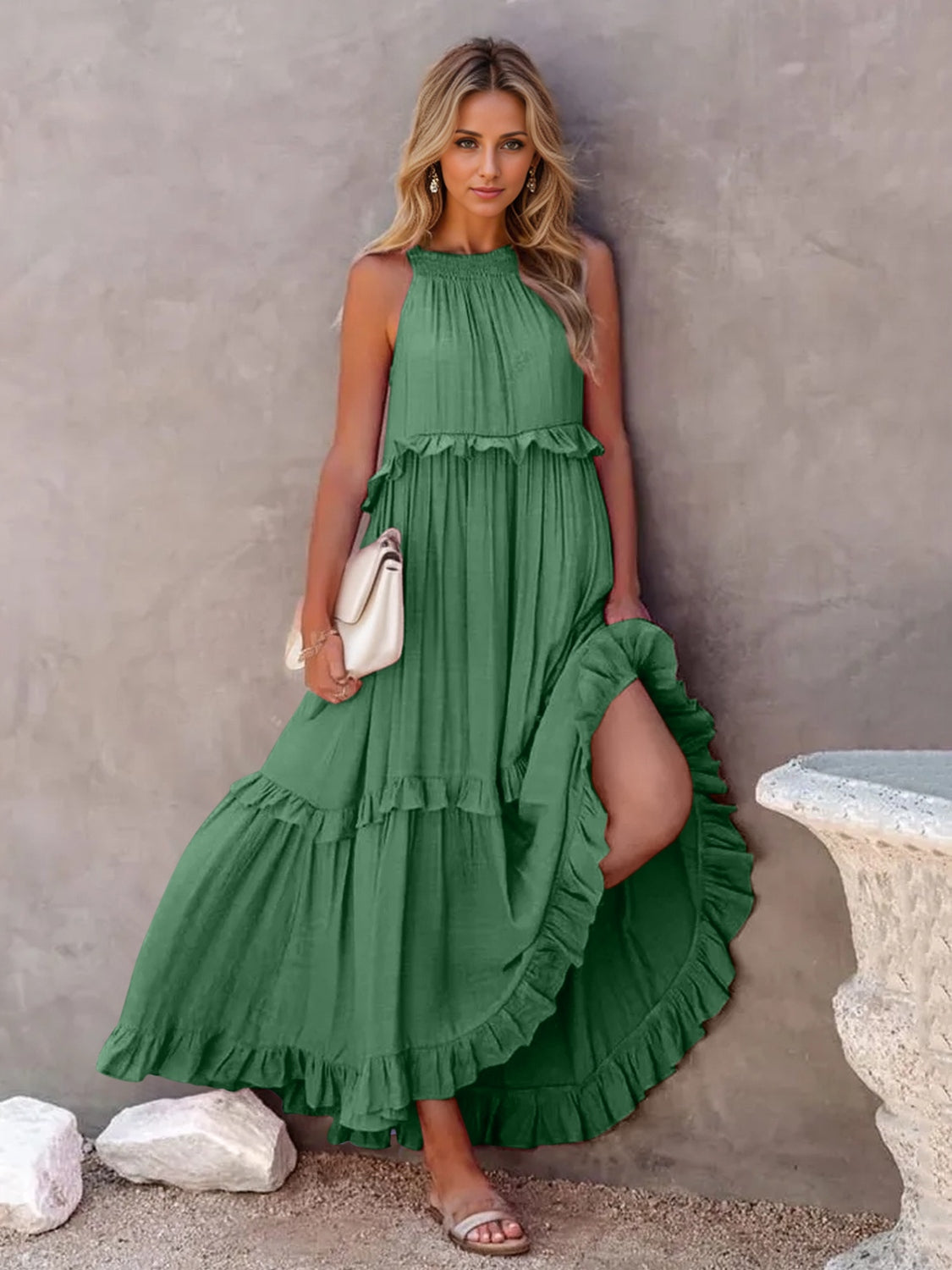 Ruffled sleeveless tiered maxi dress in green with pockets, styled with a bag, showcasing a high-low design.