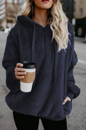 Stylish woman wearing a navy quarter-zip drawstring teddy hoodie while holding a coffee cup outdoors.